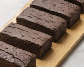 Vijf eiwitrijke brownies op een houten plank.