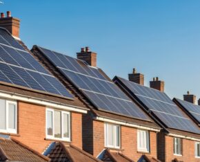 Rij woningen met zonnepanelen op de daken op een zonnige dag.